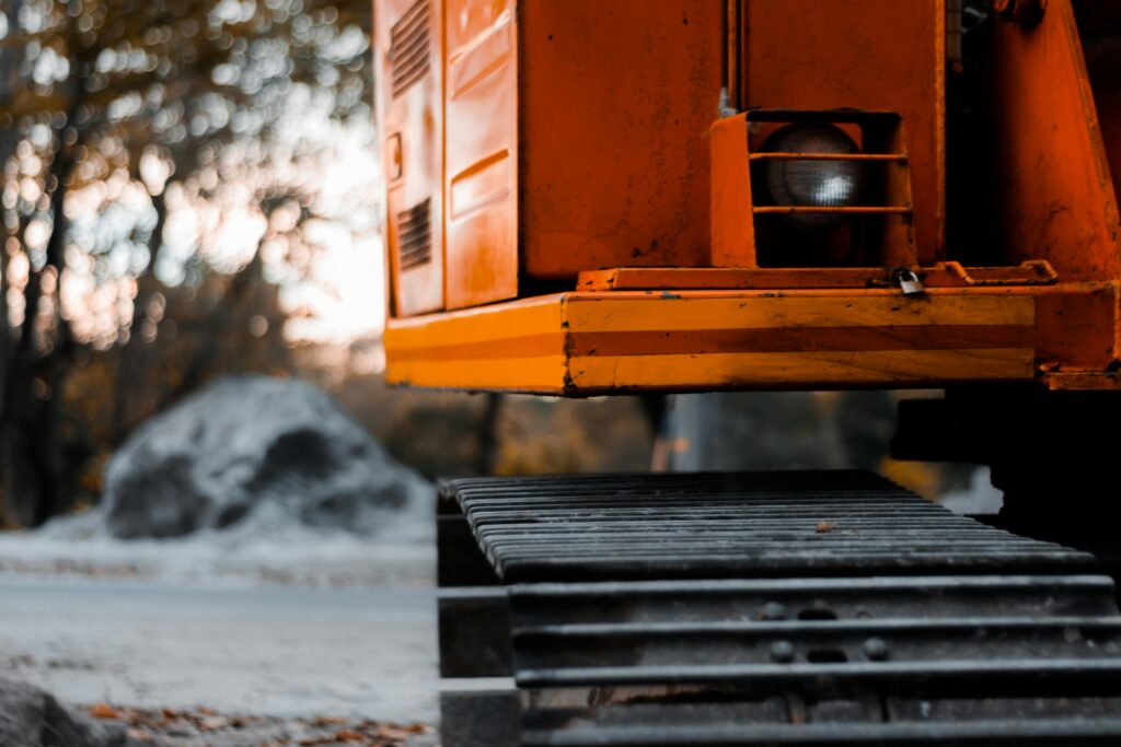 pexels-photo-1139553-1139553 Close-up shot of an orange excavator with tracks in an outdoor setting during the day.